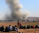 People watch as smoke and dust rise over Syrian town of Kobani after an airstrike.