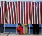 A young girl looks out from a voting booth as her mother casts her ballot at the Bishop Leo O'Neil Youth Center on November 6, 2012 in Manchester, New Hampshire.